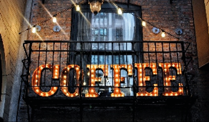 An interior illuminated signage display, creating a warm and inviting atmosphere within a coffee shop. Illuminated internal signage spelling 'COFFEE' with warm lighting.