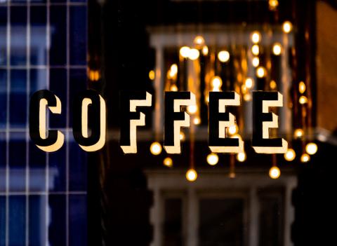 Illuminated COFFEE sign with hanging lights reflection