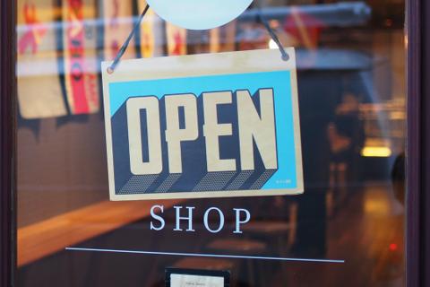 Open shop sign hanging in a store window